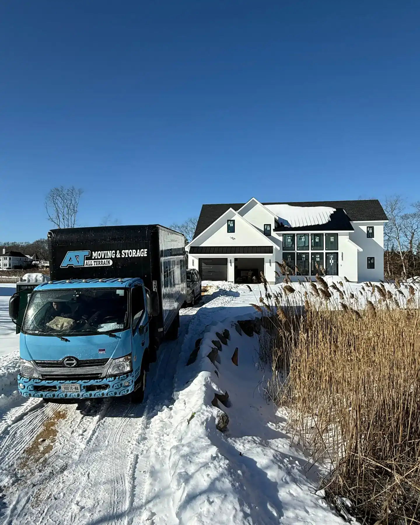 All Terrain Moving and Junk Removal truck parked outside a snowy residential home.